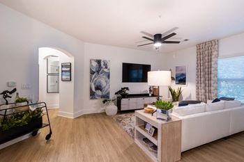 A living room with a white couch, a television, and a ceiling fan.